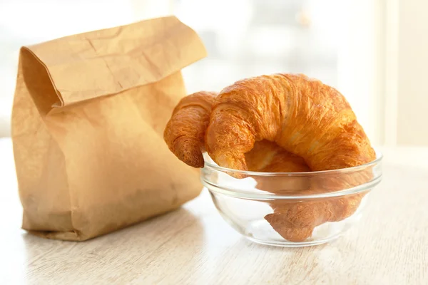 Dois croissants em uma tigela e um saco de papel — Fotografia de Stock