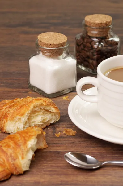 Croissants en kruimels in de buurt van een kopje koffie — Stockfoto