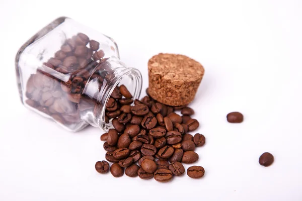 Een kleine glazen pot met verspreide koffiebonen en een kurk — Stockfoto