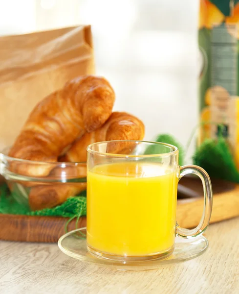 Orange juice in a transparent mug with pastries on the backgroun — Stock Photo, Image