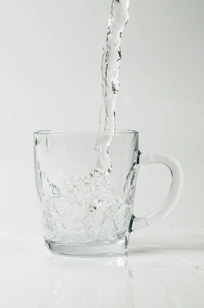 Klart vatten hälla i en glas-kopp — Stockfoto