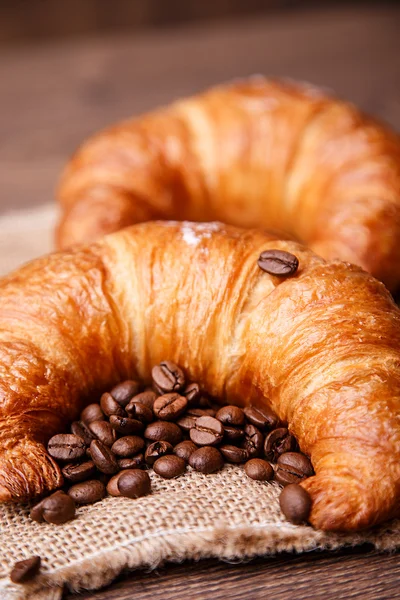 Dos croissants y granos de café en una servilleta de lino — Foto de Stock