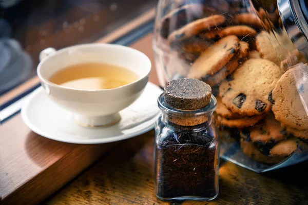 A cup of tea and chocolate chip cookies on the windowsill — Stock Photo, Image