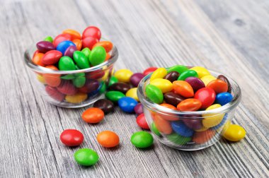Colorful coated chocolates in two glass bowls clipart