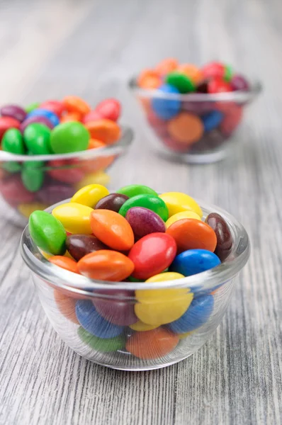 Three tiny bowls with colorful chocolate candies — Stock Photo, Image