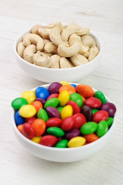 A bowl of colorful candies and a bowl of cashew nuts — Stock Photo, Image