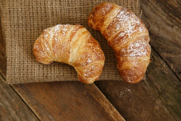 Twee suikerpoeder croissants op een houten ondergrond — Stockfoto