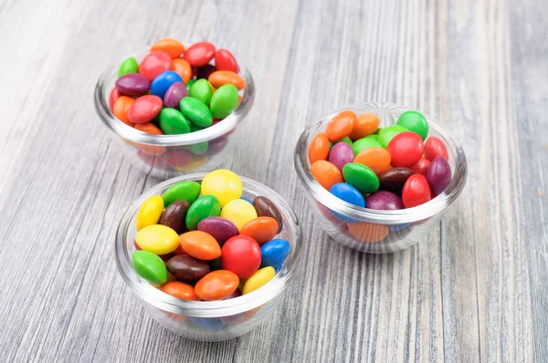 Three glass bowls with colorful crunchy treats — Stock Photo, Image