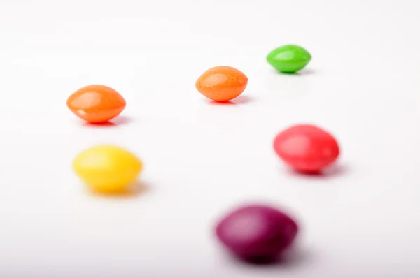 Seis doces de cor diferentes em uma superfície branca — Fotografia de Stock