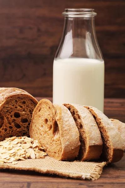 Una barra de pan crujiente y un frasco de avena —  Fotos de Stock