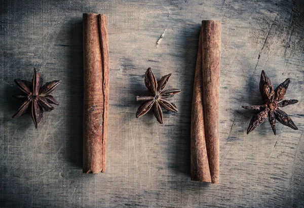 Três estrelas de anis e dois paus de canela em uma superfície de madeira — Fotografia de Stock