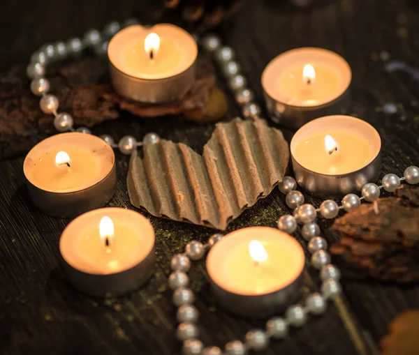 Seis velas de té alrededor de un corazón de papel y perlas —  Fotos de Stock