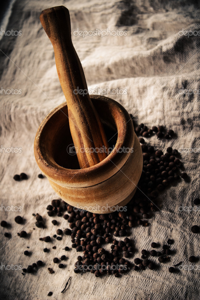 Mortero y mortero de madera y pimienta de Jamaica sobre lino 2023
