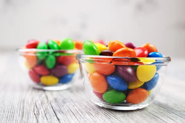 Zwei Schalen mit bunten Bonbons auf ungesättigtem Hintergrund — Stockfoto