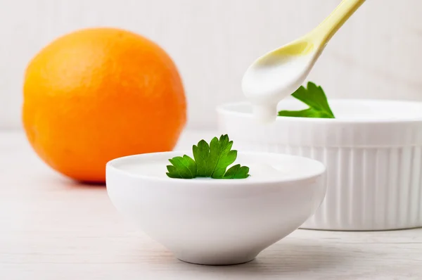 Un'arancia e due ciotole bianche con yogurt bianco denso — Foto Stock