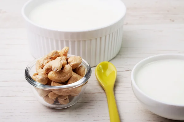 A bowl of nuts and two bowls with milk product — Stock Photo, Image