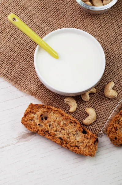 Een kom met yoghurt en een stuk knapperige brood — Stockfoto