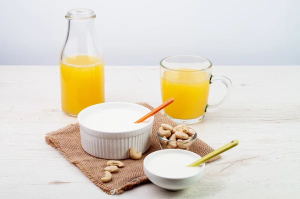 Yogurt with a bottle of juice and a bowl of nuts — Stock Photo, Image