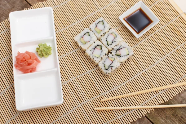 Sushi on a bamboo mat and an empty plate — Stock Photo, Image