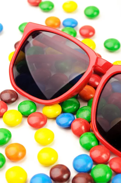 Óculos de sol vermelhos em doces revestidos de cor de chocolate — Fotografia de Stock