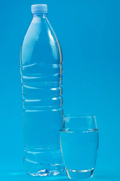 Láhev a sklenice na modrém pozadí — Stock fotografie