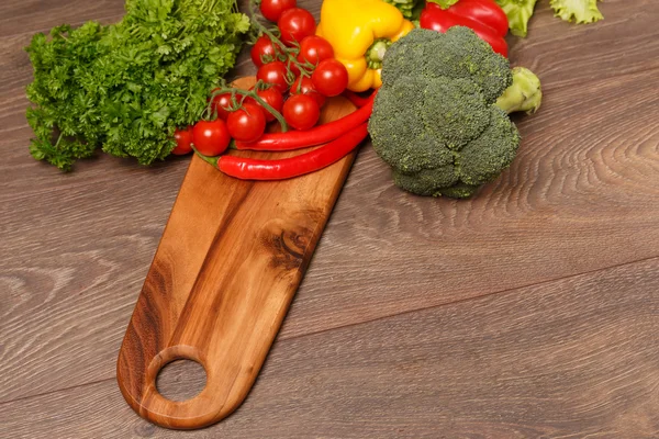 Tomatoes and broccoli on a wooden cutting board — Stock Photo, Image