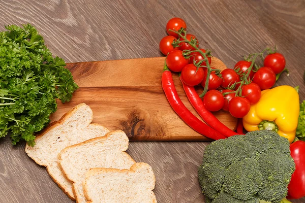 Tomates, pan y otras cosas en una tabla de cortar —  Fotos de Stock