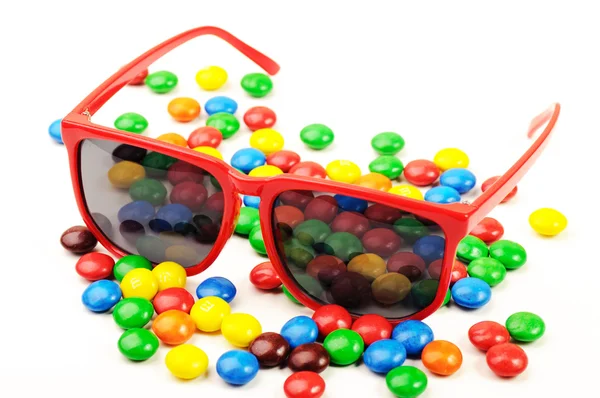 Plastic red sunglasses and different color sweets — Stock Photo, Image