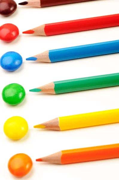 Different color pencils and same color candies — Stock Photo, Image