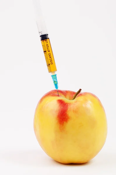 A yellow apple with a yellow syringe in it — Stock Photo, Image