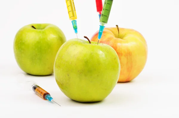 Two green apples and a yellow one with colorful syringes — Stock Photo, Image