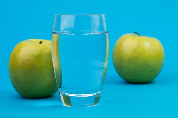 Sklenici s vodou a dvě zelená jablka — Stock fotografie
