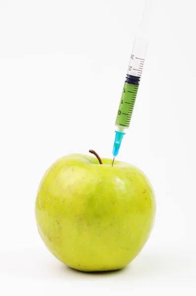 Green syringe stuck in a green apple — Stock Photo, Image