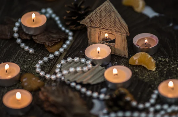 Tea candles and pearls with a cardboard house — Stock Photo, Image