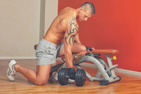 Homem bonito com músculos levantar um halteres — Fotografia de Stock