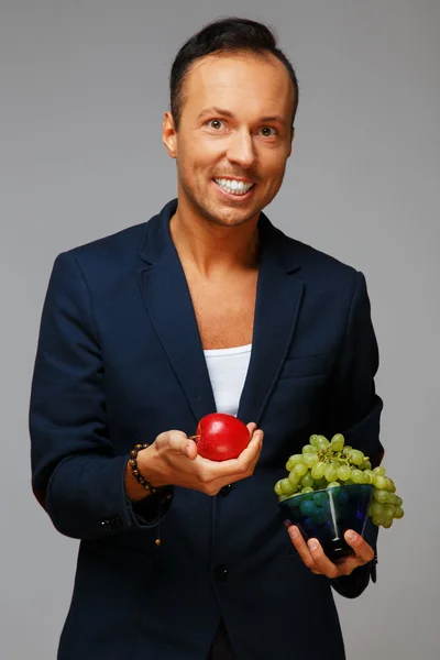 Чоловік з яблуком і виноградом — стокове фото