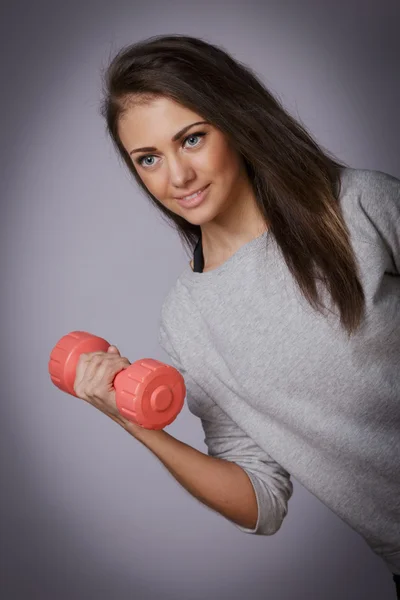 Femme avec un haltère dans un haut de sport gris — Photo