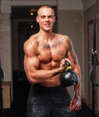 Mutlu genç adam bir spor salonunda bir ağırlık tutarak