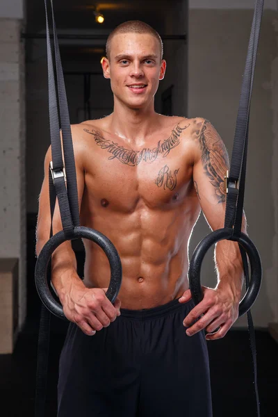 Muskulöser tätowierter Mann, der mit Ringen trainiert — Stockfoto