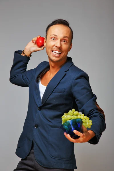 Человек с яблоком и виноградом — стоковое фото
