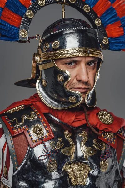 Стародавній імператорський легіонер з шоломом на сірому фоні — стокове фото