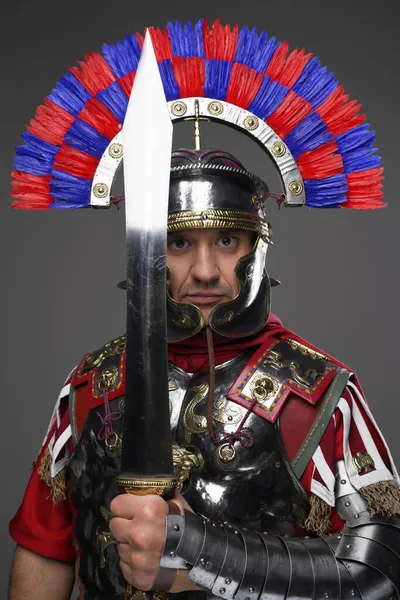 Legionário romano posando com espada isolada em cinza — Fotografia de Stock