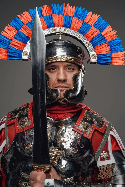 Stolzer römischer Soldat mit Gladius posiert vor grauem Hintergrund — Stockfoto