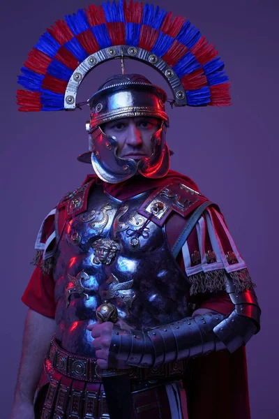 Powerful roman centurion posing against purple studio background — Stock Photo, Image