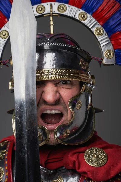Schreiender Legionär mit kurzem Schwert vor grauem Hintergrund — Stockfoto