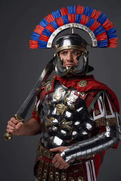 Antique pensive legionary posing against gray studio background — Stock Photo, Image