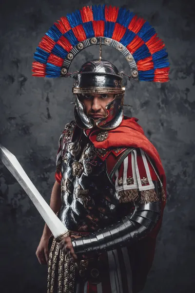 Серьезный легионер с гладиусом, позирующий на тёмном фоне — стоковое фото