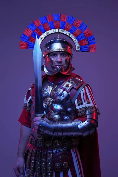 Tiro de soldado romano antigo posando em luz escura colorida — Fotografia de Stock