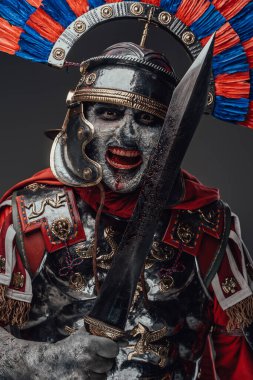 Gri üzerine izole edilmiş gladyatörle poz veren zalim zombi yüzbaşısı.