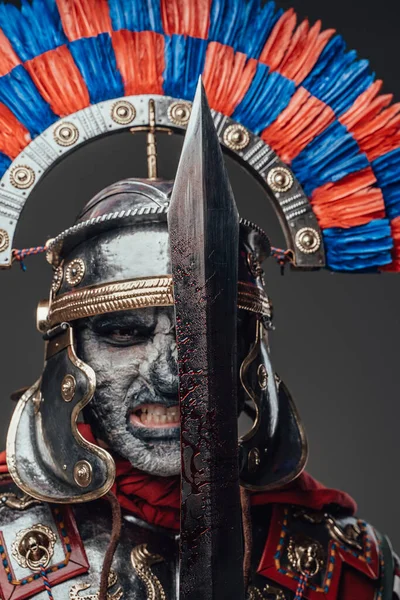 Мертвий римський солдат з кривавим мечем на сірому фоні — стокове фото